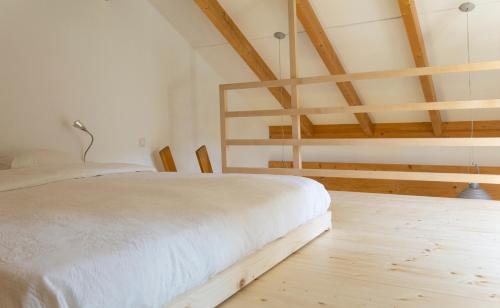 Una cama blanca en una habitación con techos de madera. en Rückzugsort mitten im Paradies en Feldafing