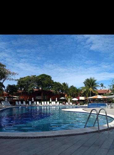 a large swimming pool with chairs and umbrellas at Resort All Inclusive Arcobaleno in Porto Seguro