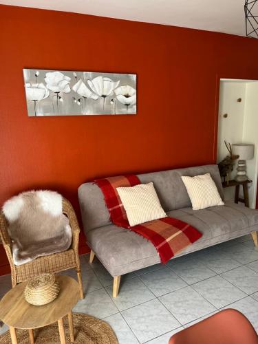 a living room with a couch and a chair at L'enclos bleu, gîte - marais poitevin avec piscine chauffée in Chaillé-les-Marais