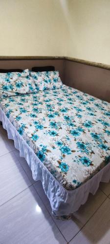 ein Bett mit blauen Blumen auf einem Zimmer in der Unterkunft Pousada e Hostel clubhouse in Camassari