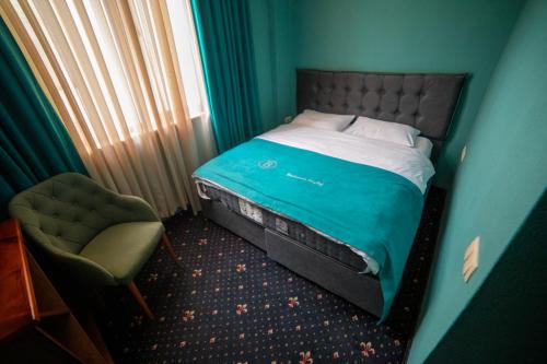 a small bedroom with a bed and a chair at Belona Hotel in Kutaisi