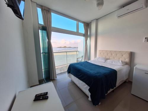 a bedroom with a bed with a view of the ocean at Suítes Pitangueiras in Guarujá