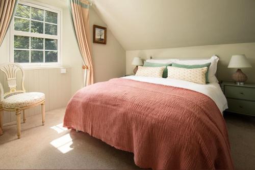 a bedroom with a bed with a red blanket and a chair at Wood Cottage in Coldstream