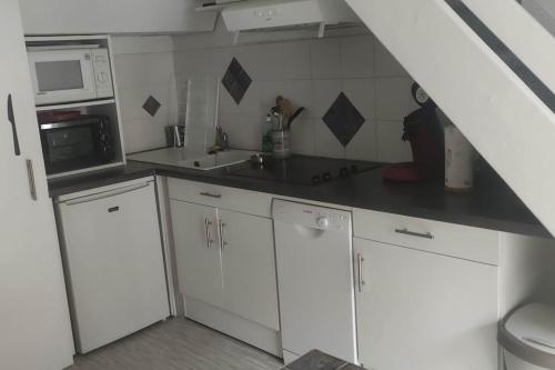 una cucina con mobili bianchi, un lavello e un microonde di Appartement de 2 à 6 personnes a Cauterets