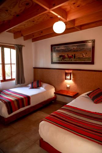 a bedroom with two beds and a painting on the wall at Tambo Atacama Lodge in San Pedro de Atacama