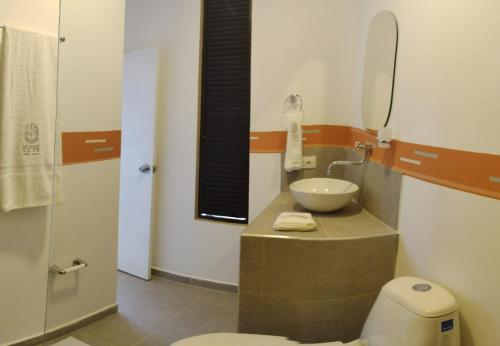 uma casa de banho com um lavatório, um WC e um espelho. em VerdeSelva em Doradal