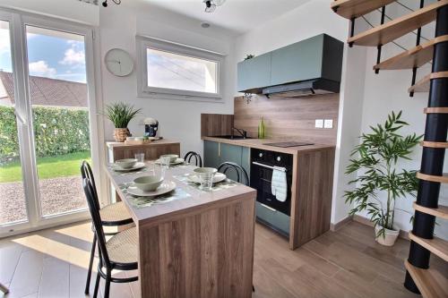 une cuisine avec une table et des chaises dans une pièce dans l'établissement Joli appartement en duplex neuf à Saint-Josse, à Saint-Josse