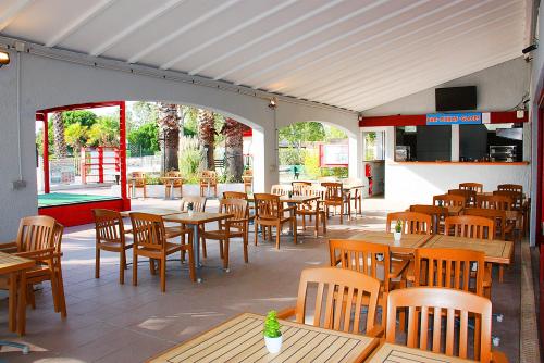 un restaurant vide avec des tables et des chaises en bois dans l'établissement Azureva Le Grau du Roi, au Grau-du-Roi