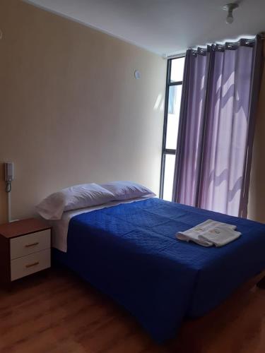 Un dormitorio con una cama azul y una ventana en Hotel Samanahuasi nasca en Nazca
