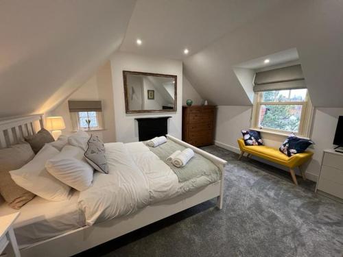 um quarto com uma cama grande e um sofá amarelo em The Loft at Scalford House em Melton Mowbray