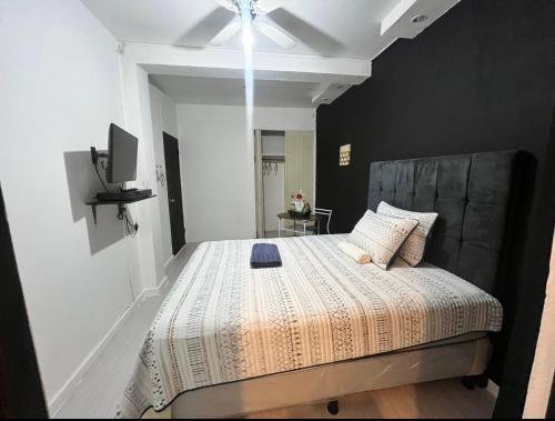 a bedroom with a large bed with a gray headboard at Habitación #2 in San Salvador