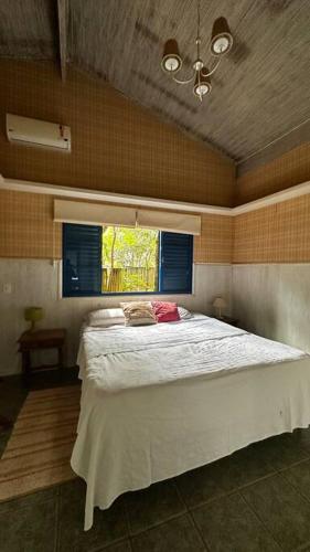Schlafzimmer mit einem großen weißen Bett und einem Fenster in der Unterkunft Chácara Cajueiro in Araras