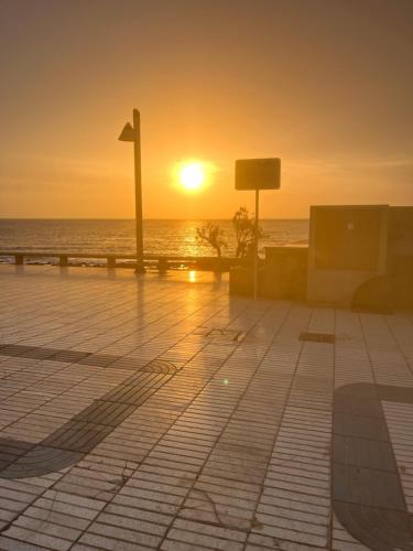 una puesta de sol en la playa con el océano en el fondo en Paraíso Playa de Arinaga en Arinaga