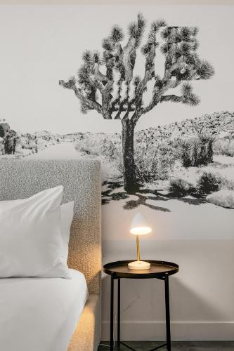 a bed and a table with a lamp next to a tree at Papago Scottsdale by Reside, Trademark Collection by Wyndham in Scottsdale
