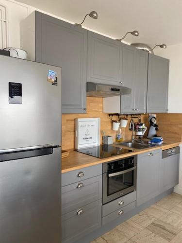 a kitchen with a stainless steel refrigerator and wooden counters at Vue BAIE XXL 180° in Le Crotoy