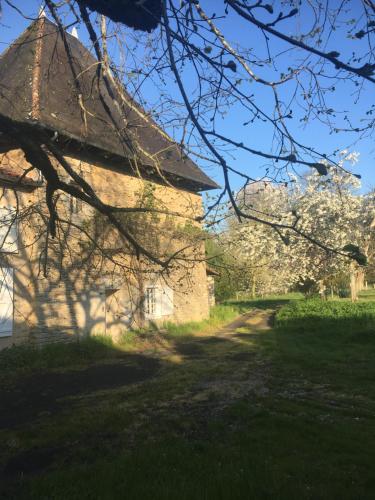 un bâtiment en pierre avec un arbre en face dans l'établissement gite en pleine campagne au bord de la rivière, à Joussé