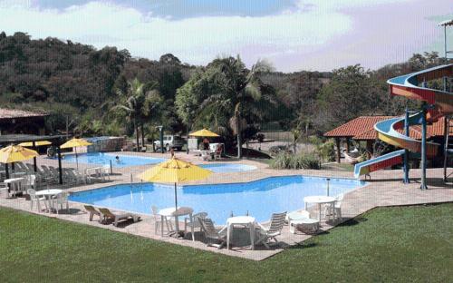 a large swimming pool with chairs and umbrellas at Hotel Fazenda Reviver in Araçoiaba da Serra