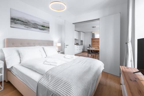 a white bedroom with a white bed and a dining room at VISIMO Apartments Chur in Chur