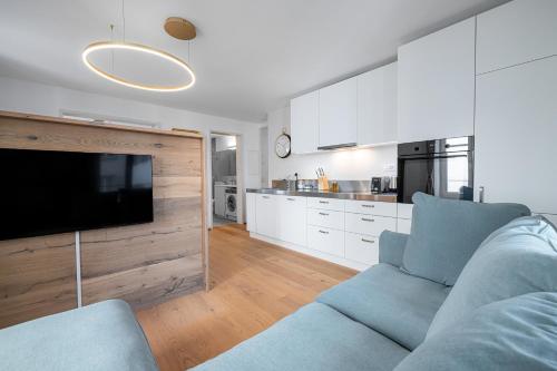 a living room with a blue couch and a kitchen at VISIMO Apartments Chur in Chur