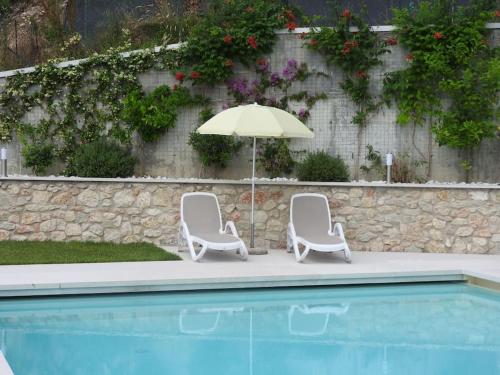 two chairs and an umbrella next to a pool at Appartamenti Annachiara in Costermano sul Garda