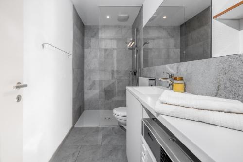 a bathroom with a white sink and a toilet at VISIMO Apartments Chur in Chur