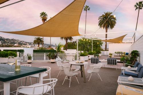patio ze stołami, krzesłami i palmami w obiekcie Beverly Terrace powered by Sonder w Los Angeles