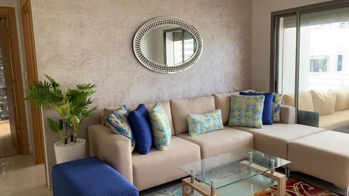 a living room with a couch and a mirror at Très bel appartement neuf à Mansbay Manssouria in Mohammedia