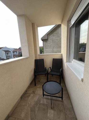 two chairs and a table in a balcony with a window at Residence 25V in Batajnica
