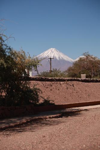 a snow covered mountain in the distance with a road at Tambo Atacama Lodge in San Pedro de Atacama