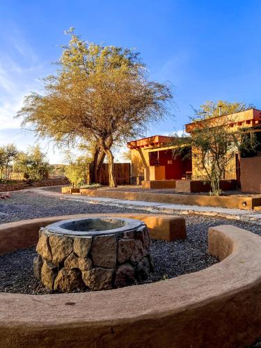 a fountain in a park with a tree and a building at Tambo Atacama Lodge in San Pedro de Atacama