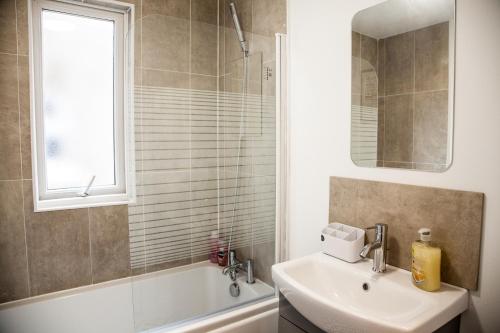 uma casa de banho com um lavatório, um espelho e uma banheira em MantonHouse by Sheryl - Sleeps 7 em Liverpool