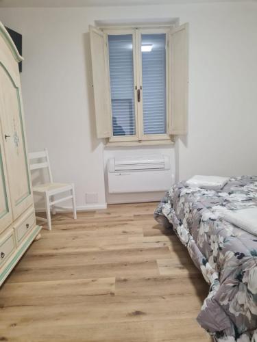 1 dormitorio con cama, ventana y suelo de madera en AFFITTA CAMERE MAZZATINTI, en Gubbio