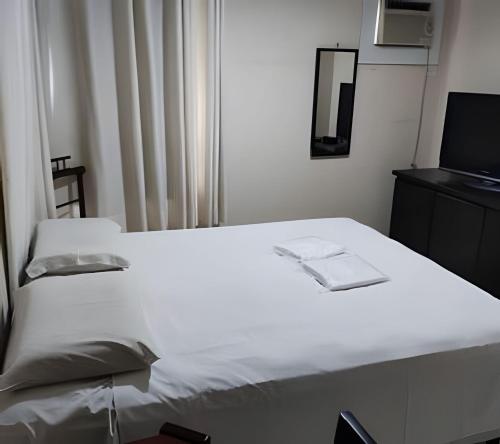 a bedroom with a white bed and a television at Apart Acolhedor 5 pessoas Hakka Eventos, Hospitais e Feirinha in Sao Paulo