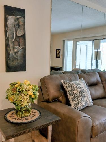 a living room with a brown couch and a table with flowers at Welcome to Midtown Condo in Little Rock