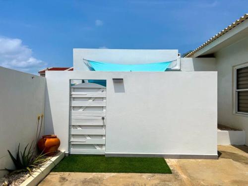 a white wall with a ladder next to a house at Paradise Studio Aruba in Palm-Eagle Beach