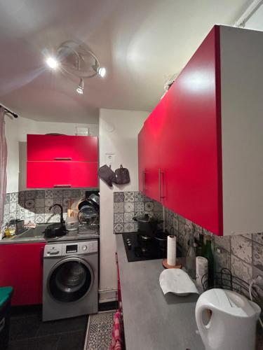 - une cuisine avec des placards rouges et un lave-linge dans l'établissement Eunila appart 15’ Défense, proche Paris, à Bezons