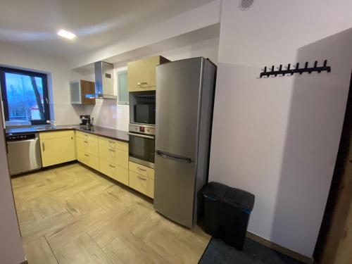 a kitchen with a stainless steel refrigerator and yellow cabinets at Apartamenty JENDRYCÓWKA in Korbielów