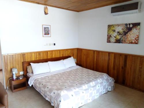 ein Schlafzimmer mit einem Bett mit einer Holzwand in der Unterkunft Hotel Palm Rock Beach in San-Pédro