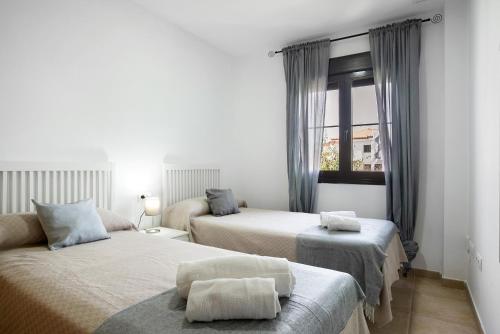 a bedroom with two beds and a window at Apartamento Coto 108 in Chiclana de la Frontera