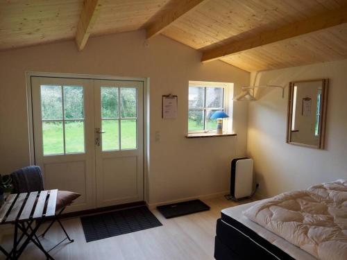 1 dormitorio con cama, mesa y ventanas en Luksus i lønstrup, med kunsten i hovedfokus M en Lønstrup