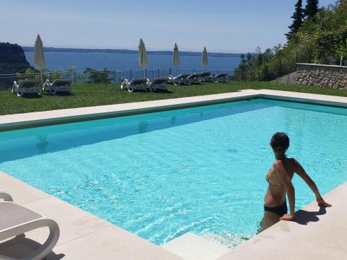 Una donna in bikini in piedi in piscina di Appartamenti Annachiara a Costermano