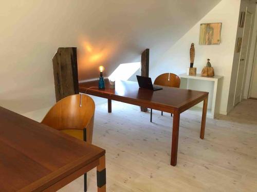 Habitación con mesa de madera con sillas y ordenador portátil. en Luksus i lønstrup, med kunsten i hovedfokus M en Lønstrup