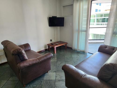 una sala de estar con 2 sofás de cuero y una mesa. en Prainha- Apart 2 quartos a 1 min da praia!, en Arraial do Cabo