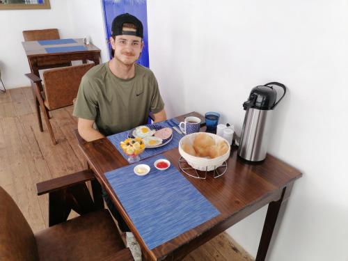 El Ave Azul Boutique Hotel Cusco في كوسكو: رجل يجلس على طاولة مع طبق من الطعام