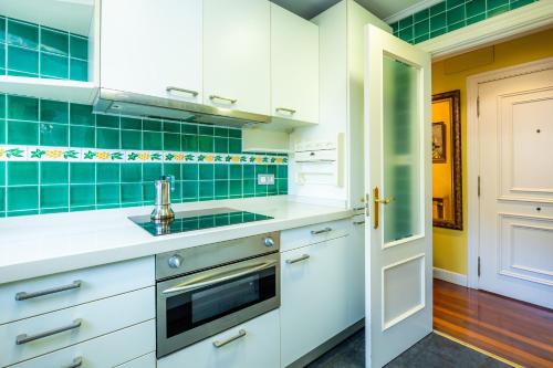 a kitchen with white cabinets and green tiles at GETXO II (Downtown, Beach and Parking) 15Min BILBAO By GrupoZTK in Getxo