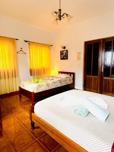 two beds in a room with yellow curtains at Casa BB&Djassi in Ponta do Sol