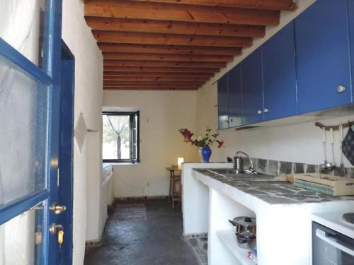 a kitchen with blue cabinets and a sink at Lovely independent room in Ecovilla on the beach in Apolakkiá