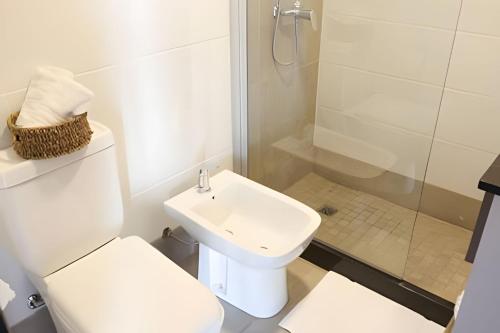 a white bathroom with a toilet and a sink at Charlie Suites en el casco histórico de Salta in Salta