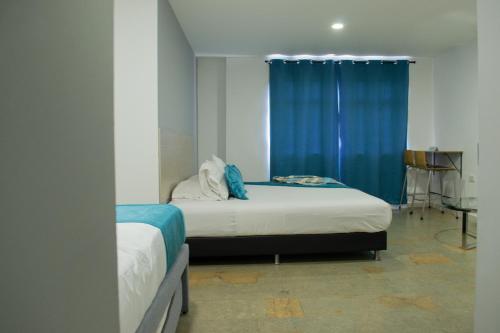 a bedroom with two beds and a blue curtain at Hotel Portón Sabaneta in Sabaneta