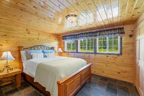 a bedroom with a bed in a wooden cabin at Dog-Friendly 3BR on 200 Acres w/ River Access in Sloat
